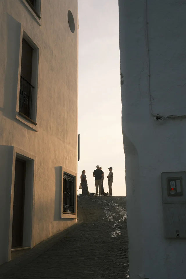 Silhouettes at the end of a narrow sunlit passage between buildings